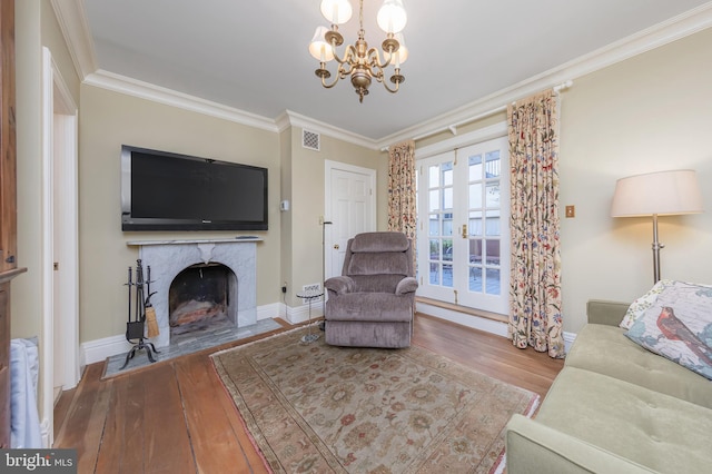 living room with hardwood / wood-style floors, a notable chandelier, a premium fireplace, and crown molding