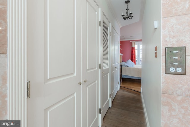 corridor with hardwood / wood-style floors, lofted ceiling, crown molding, and a chandelier