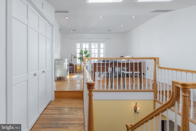 corridor featuring a skylight and light hardwood / wood-style flooring