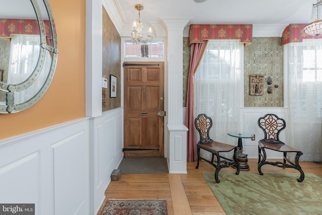 foyer featuring hardwood / wood-style flooring, an inviting chandelier, a wealth of natural light, and ornamental molding