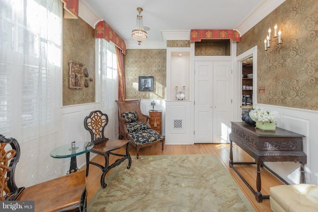 living area with light hardwood / wood-style floors, crown molding, and an inviting chandelier