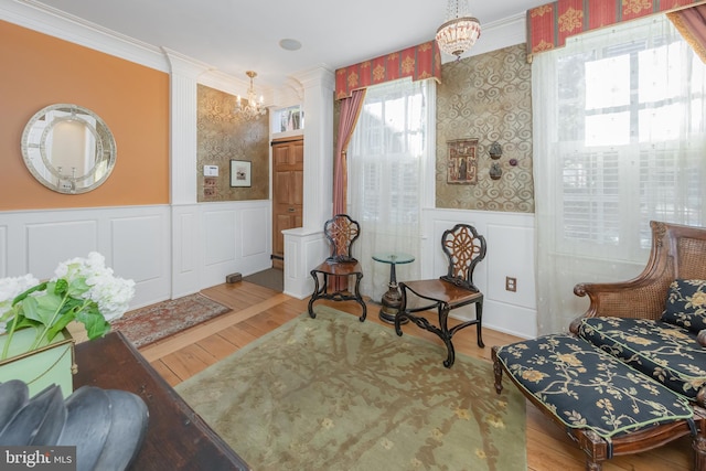 living area with ornamental molding, hardwood / wood-style flooring, a wealth of natural light, and a notable chandelier