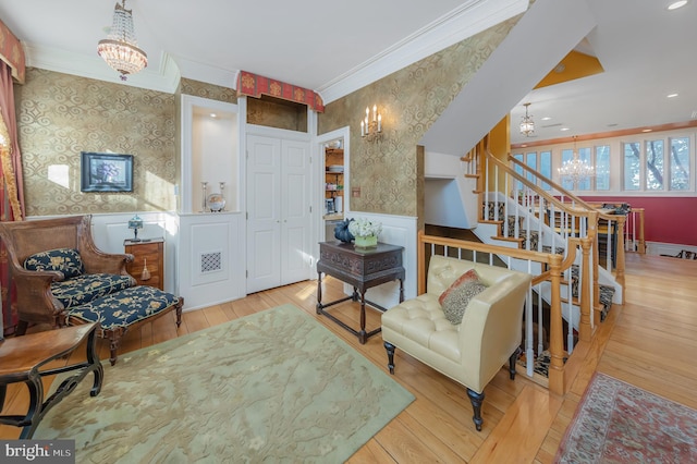 living area with a chandelier, crown molding, and light hardwood / wood-style flooring