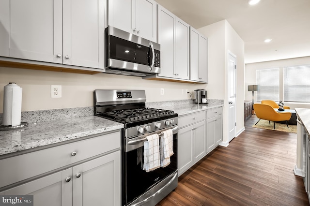 kitchen featuring dark wood-type flooring, light stone countertops, appliances with stainless steel finishes, and white cabinets