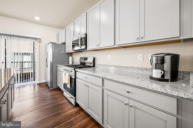 kitchen featuring dark wood-type flooring, white cabinets, light stone counters, and appliances with stainless steel finishes