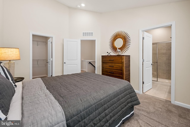 carpeted bedroom with a closet, a spacious closet, vaulted ceiling, and ensuite bath