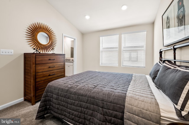 bedroom with light colored carpet, connected bathroom, and lofted ceiling