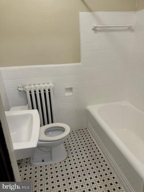 bathroom featuring radiator, tile patterned flooring, toilet, and tile walls