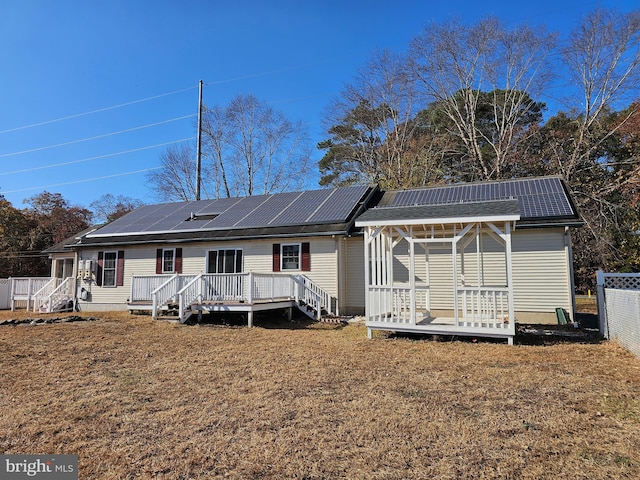 back of house with a deck and solar panels