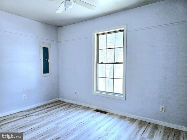 spare room featuring electric panel, ceiling fan, and light wood-type flooring