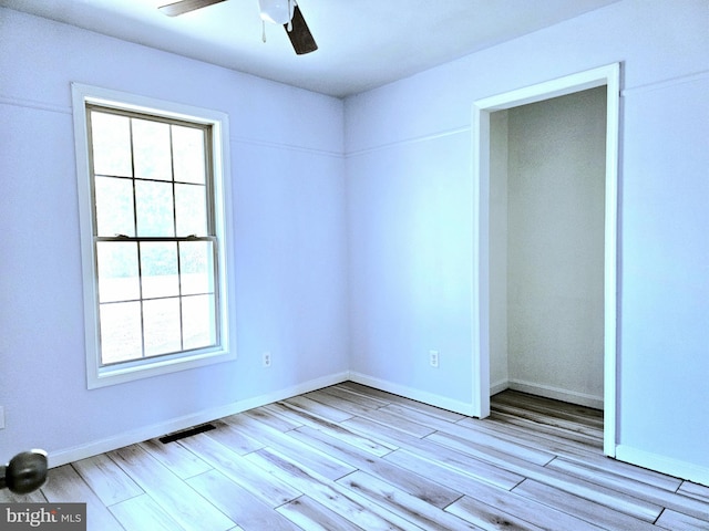 spare room with ceiling fan and light wood-type flooring