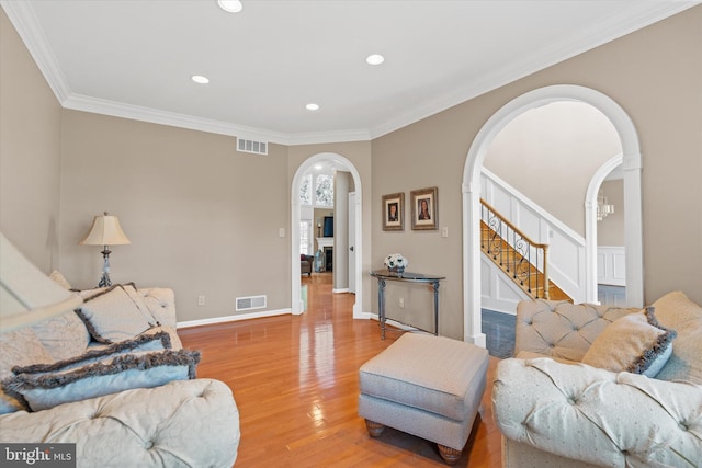 living area with arched walkways, wood finished floors, visible vents, and recessed lighting