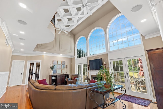 living area featuring french doors, a high ceiling, crown molding, coffered ceiling, and ceiling fan