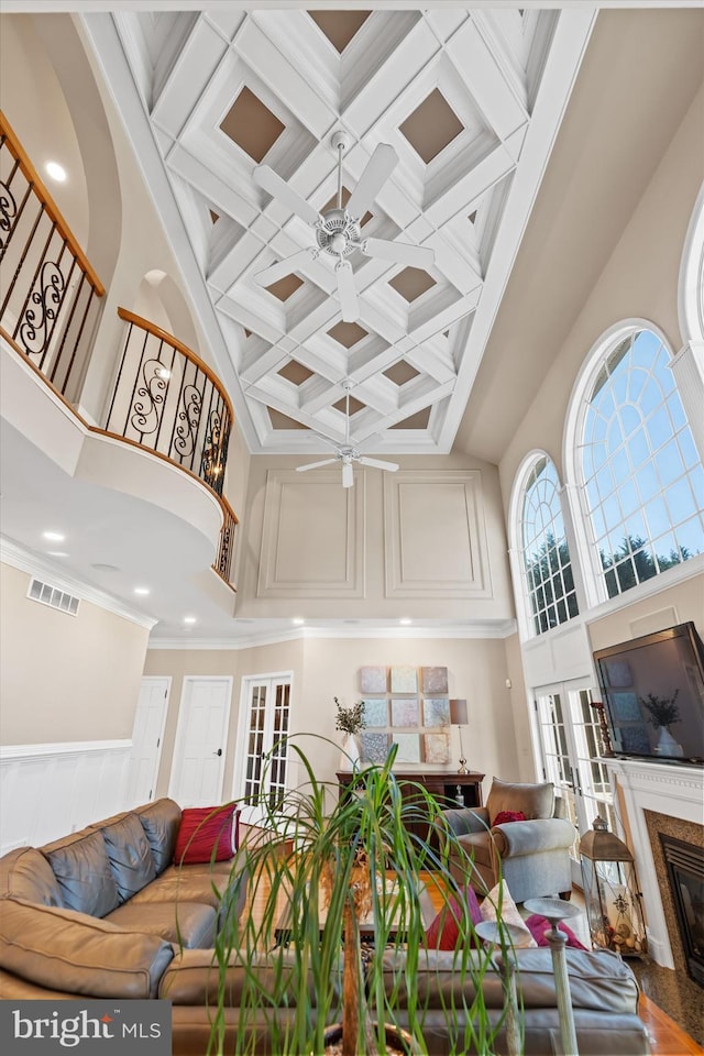 living room with ceiling fan, visible vents, a high ceiling, a premium fireplace, and coffered ceiling
