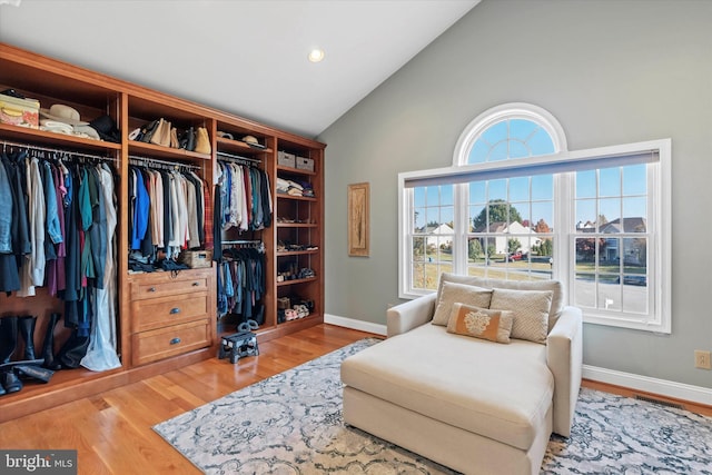 living area with high vaulted ceiling, light wood-style floors, and baseboards