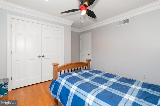 bedroom with a closet, ornamental molding, light wood-style flooring, a ceiling fan, and visible vents
