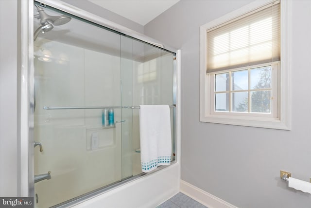 bathroom with baseboards, tile patterned flooring, and shower / bath combination with glass door