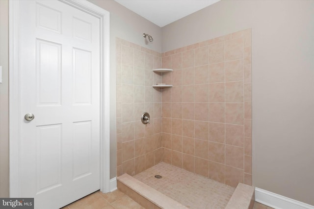 full bathroom with tile patterned flooring, baseboards, and a tile shower