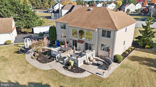 rear view of house featuring a patio, a residential view, stucco siding, and a lawn