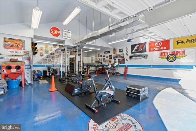 exercise room featuring high vaulted ceiling and a garage