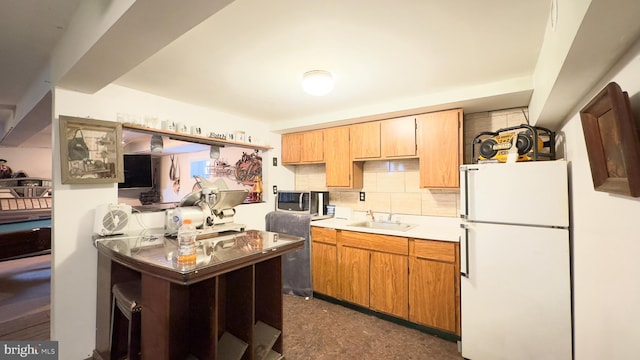 kitchen featuring white fridge, decorative backsplash, and sink