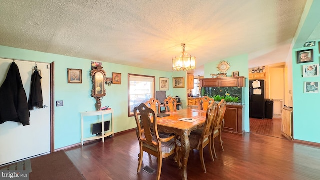 dining space featuring dark wood-type flooring, a textured ceiling, and an inviting chandelier