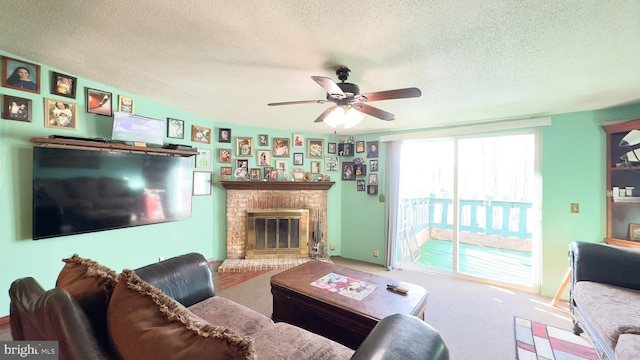 living room featuring a brick fireplace, ceiling fan, a textured ceiling, and carpet