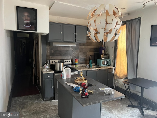 kitchen with stainless steel appliances, a center island, sink, gray cabinets, and backsplash