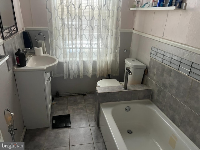 bathroom featuring toilet, vanity, tile patterned floors, and a bath