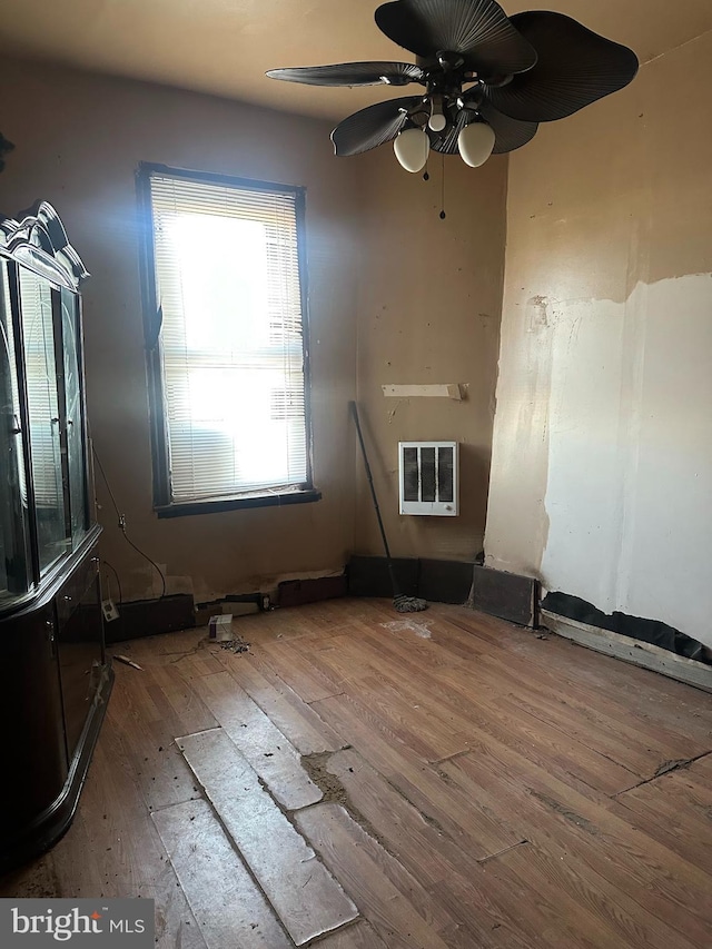 unfurnished room with ceiling fan, wood-type flooring, and heating unit