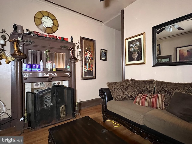 living room featuring a tiled fireplace, hardwood / wood-style flooring, and ceiling fan