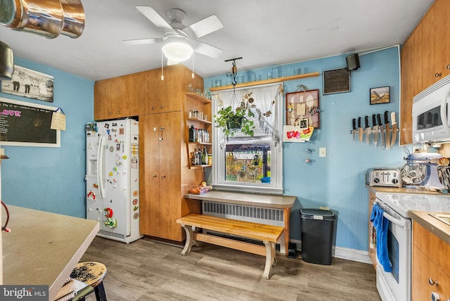 kitchen featuring decorative light fixtures, wood-type flooring, ceiling fan, and white appliances