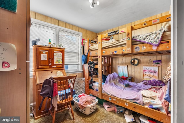 carpeted bedroom featuring wood walls