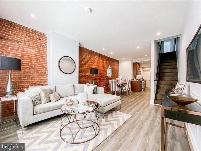 living room with light hardwood / wood-style floors and brick wall