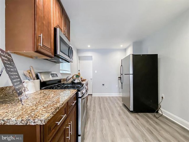 kitchen featuring appliances with stainless steel finishes, light stone counters, and light hardwood / wood-style flooring