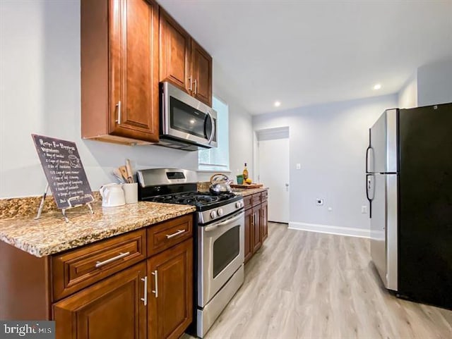 kitchen with light hardwood / wood-style flooring, light stone counters, and stainless steel appliances