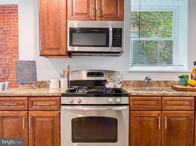 kitchen with appliances with stainless steel finishes, sink, and light stone countertops