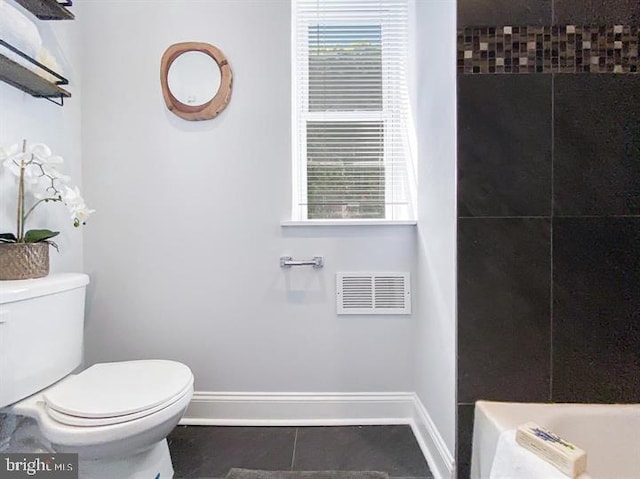 bathroom featuring tile patterned flooring, tiled shower, and toilet