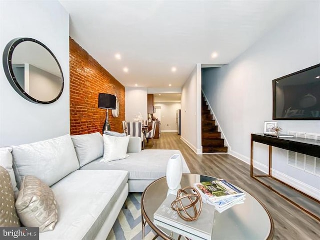 living room featuring hardwood / wood-style flooring and brick wall