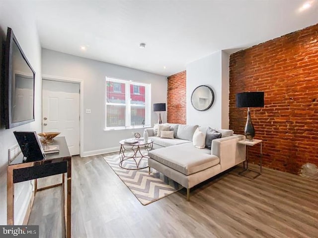 living room with hardwood / wood-style flooring and brick wall