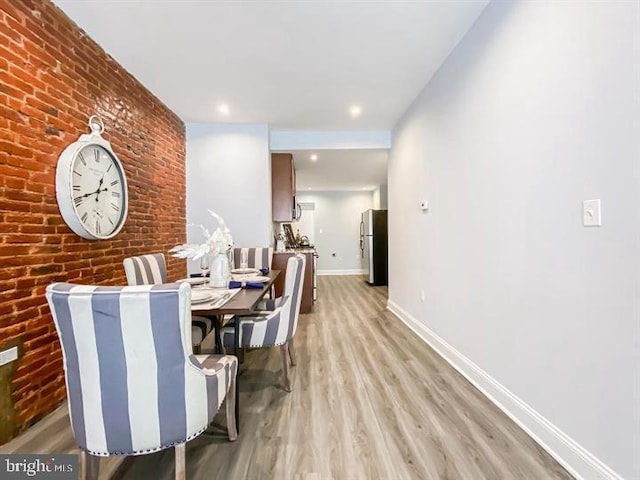 dining room with light hardwood / wood-style floors and brick wall