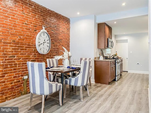 dining room with light wood-type flooring and brick wall