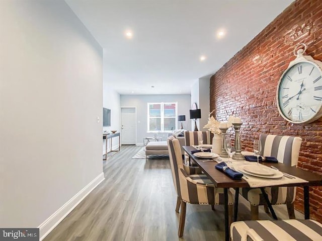 dining area with light hardwood / wood-style floors and brick wall