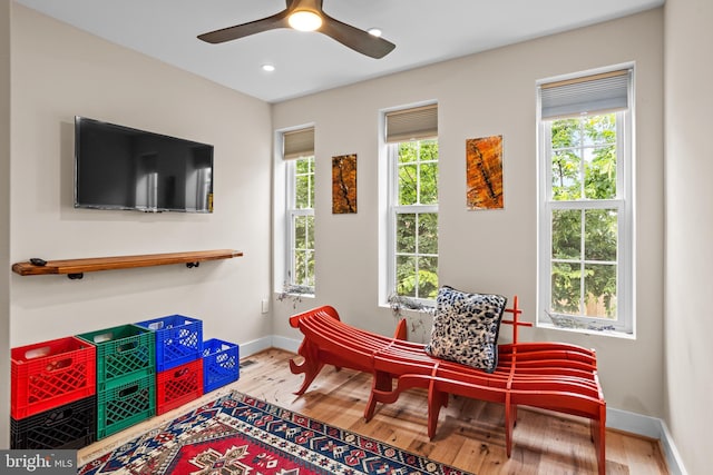 sitting room featuring ceiling fan, wood-type flooring, and a healthy amount of sunlight