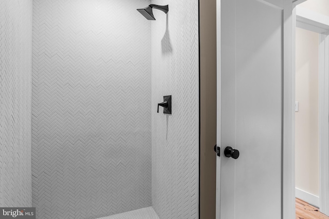 room details with wood-type flooring and tiled shower