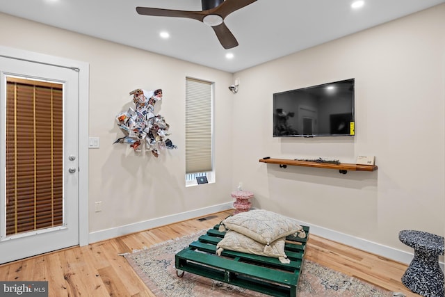 sitting room with ceiling fan and wood-type flooring