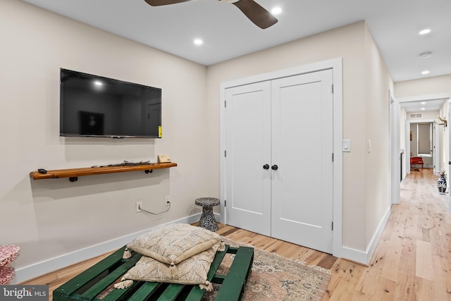 exercise room featuring ceiling fan and light hardwood / wood-style floors