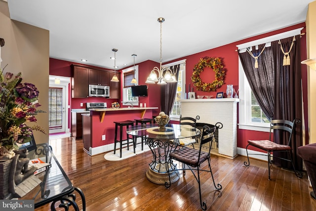 dining room featuring sink, dark hardwood / wood-style flooring, a fireplace, and an inviting chandelier