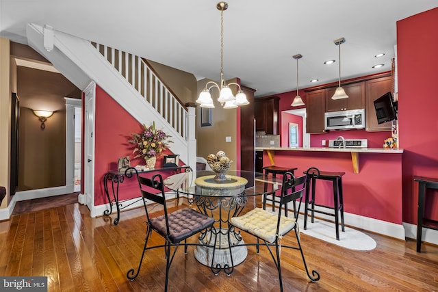 dining area with hardwood / wood-style floors, a notable chandelier, and sink