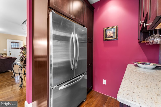 kitchen with dark hardwood / wood-style floors, light stone counters, and stainless steel refrigerator